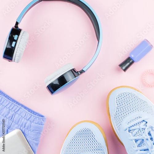 Woman sneakers, headphones, fitness tracker and running clothes on pastel background. Sport fashion concept. Flat lay