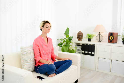 young woman at home practicing yoga and meditation with smartphone application