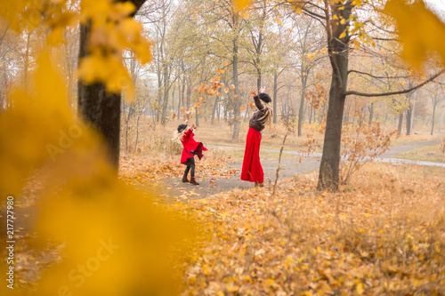 young mother plays with her little daughter in the autumn garden