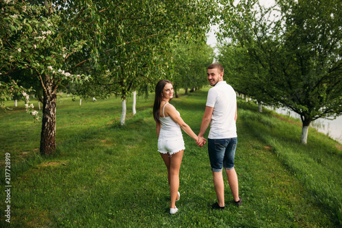 Dating in park. Love couple walking together on grass near the lake. Romance and love