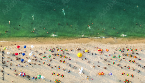 Aerial view of a beach with colorful umbrellas, people swimming in the sea, sunny day. Drone landscape from above photo