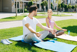 Yoga partners. Delighted attractive woman looking at her friend while sitting in the lotus pose