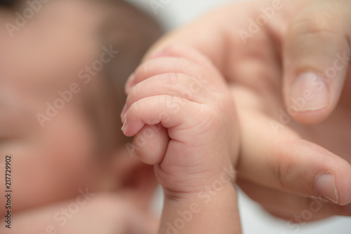 Newborn baby holding finger of mother / father. Happy Family and Baby protection concept. Mom and dad holding the hand of their child.