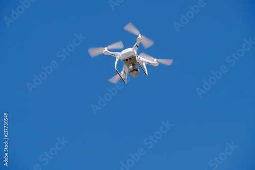 White drone for photography flies in the blue sky