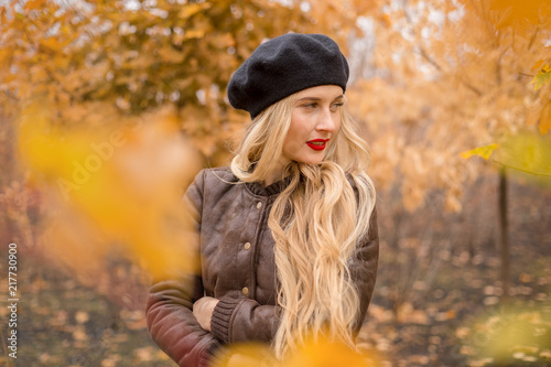 girl in a black beret with bright red lips against the backdrop of an autumn garden
