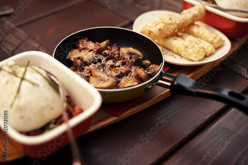 Roasted mushrooms with onion in frying pan over wooden background