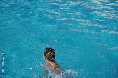 Teenager wet hair from behind sitting in swimming pool alone blue water © Marina