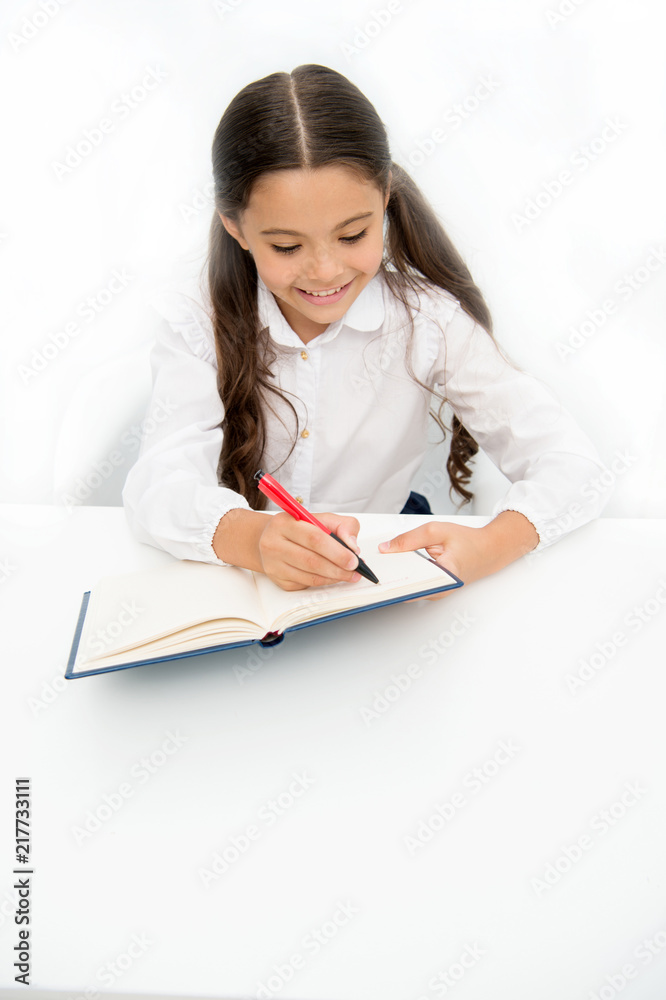 Little bookworm. Writing notices. Girl child writes hometask while sit table white background. Schoolgirl studying writing notice. Kid girl school uniform happy face writes exercise, copy space Little bookworm. Writing notices. Girl child writes hometask while sit table white background. Schoolgirl studying writing notice. Kid girl school uniform happy face writes exercise, copy space