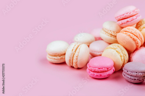 The row of colorful macarons on pink background.
