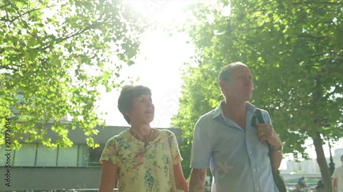 Slow motion steady cam view of an active senior caucasian tourist couple walking in london backlit by the sun themes of sightseeing active seniors direction on the move