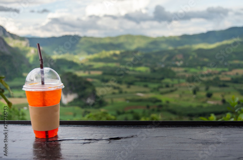 Iced tea Put on black wooden table with blurred soft nature and mountain range background to drink concept. photo