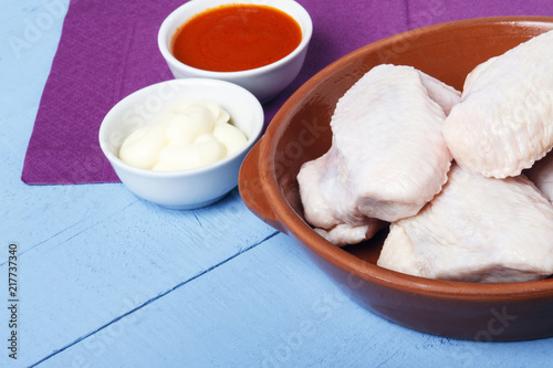 Fresh chicken wings, tomato sauce and mayonnaise on a wooden table. Copy space