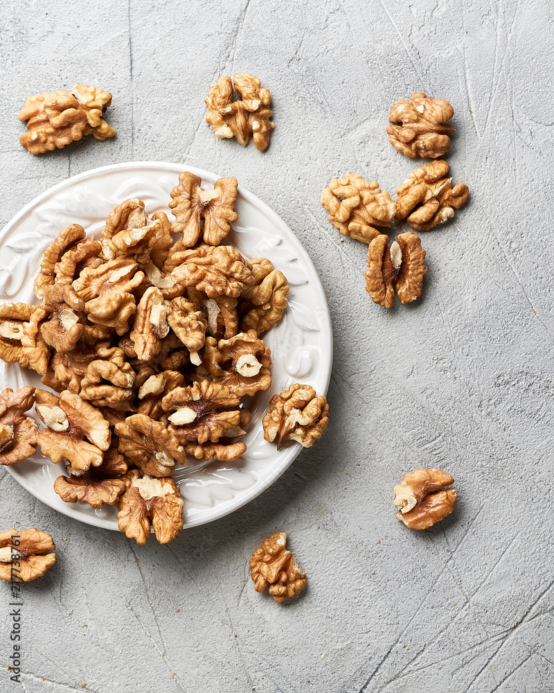 Walnut kernels on white plate over gray background.