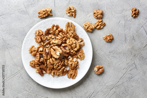 Walnut kernels on white plate over gray background.