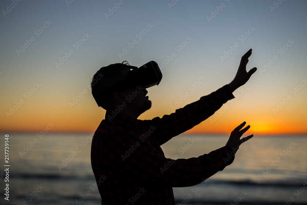 Virtual Realty is here man wearing virtual reality glasses on the over beautiful sea and sky background