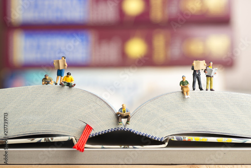 Close up of miniature figures of a group of people read book and newspaper. photo