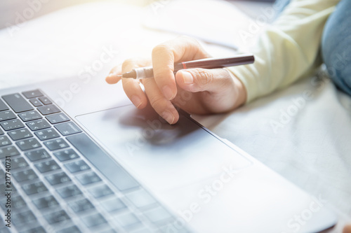 Soft scene of woman hand holding pen and searching data on internet from notebook computer at home office.