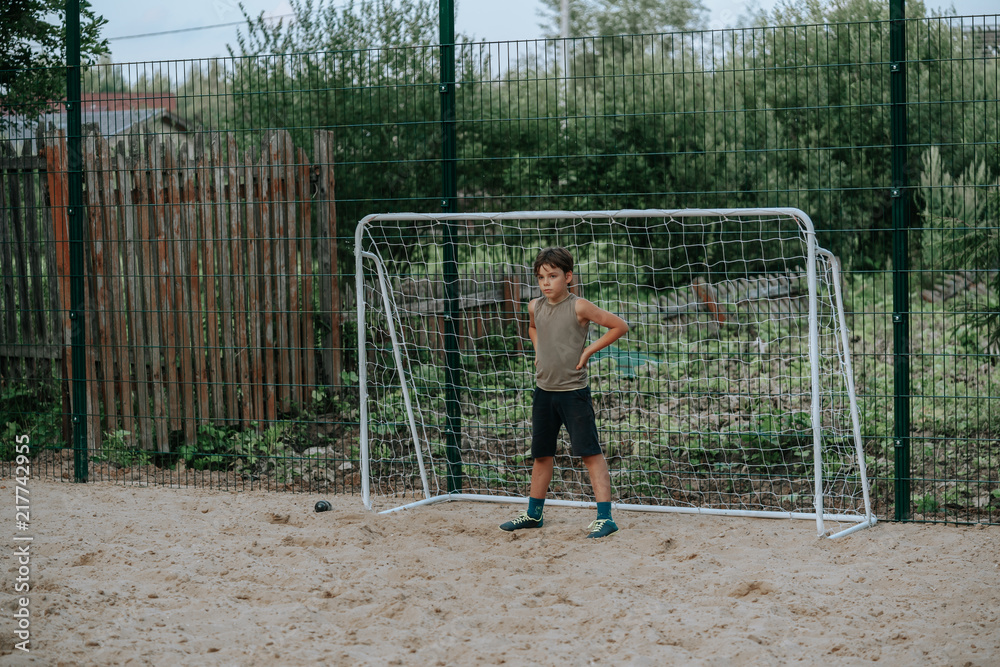 Boy football player standing at the gate on the football pitch Boy football player standing at the gate on the football pitch