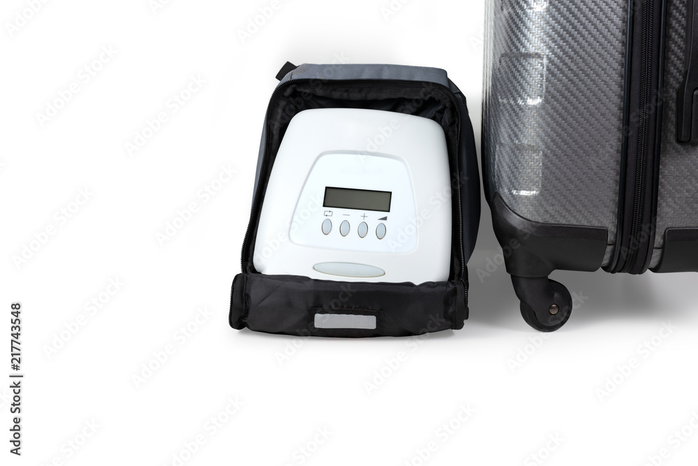 CPAP portable . CPAP machine in small bag laying beside traveling bag ready for a trip,isolated on white background with clipping path. CPAP portable . CPAP machine in small bag laying beside traveling bag ready for a trip,isolated on white background with clipping path.