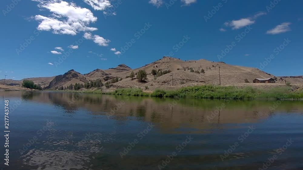 Pan shot of water with mountain range and lonely house nearby Pan shot of water with mountain range and lonely house nearby