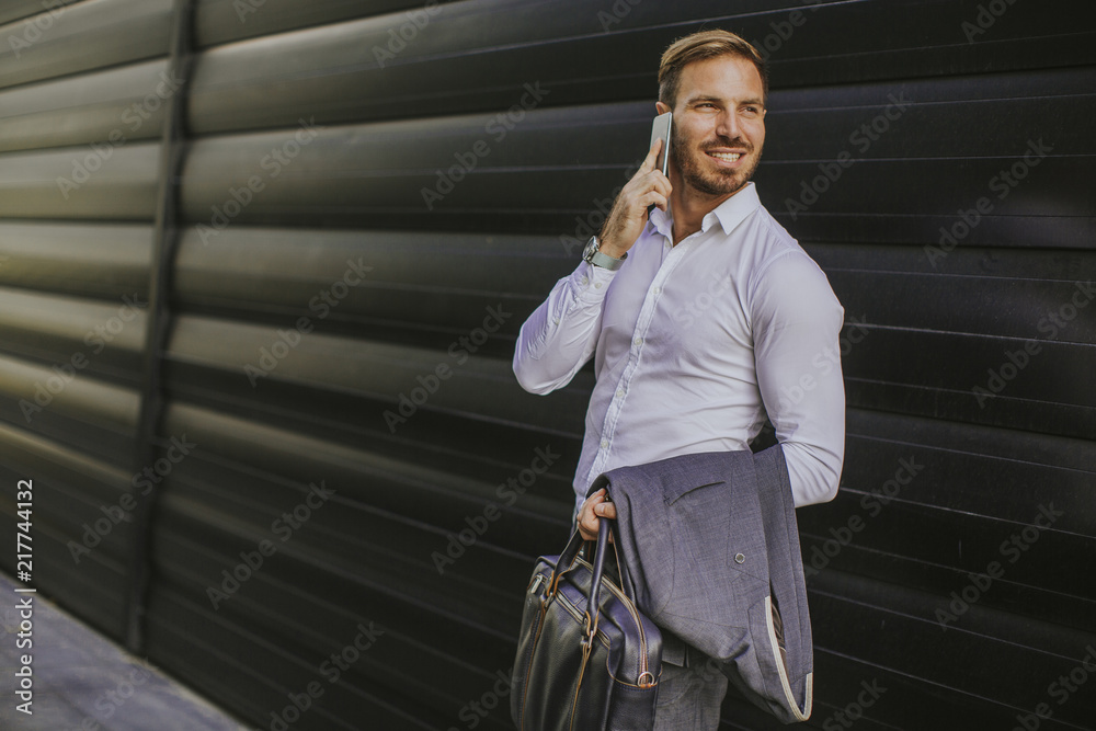 Fototapeta premium Happy smiling urban businessman using smart phone outside