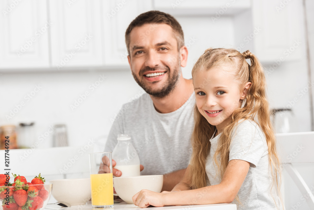 father and daughter having breakfast and looking at camera father and daughter having breakfast and looking at camera