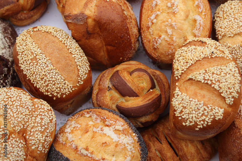Fresh fragrant bread on the table, delicious buns with sesame and poppy seeds.
