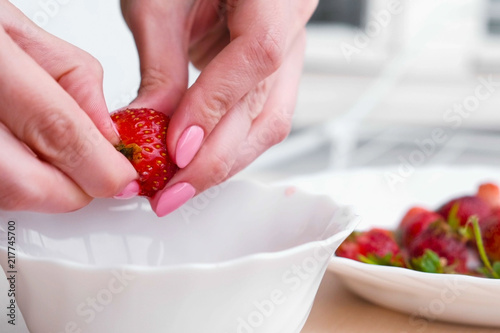 Woman cleans strawberries and puts it in a bowl. Close-up woman's hands.