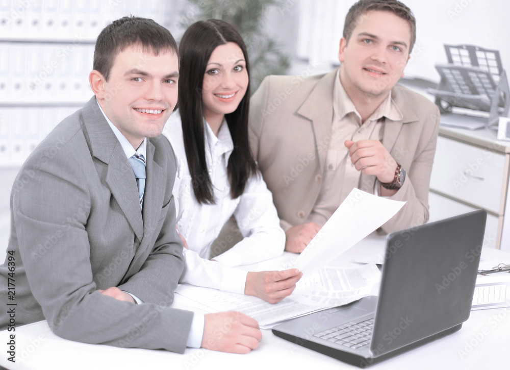 employees discussing financial charts sitting at their Desk employees discussing financial charts sitting at their Desk