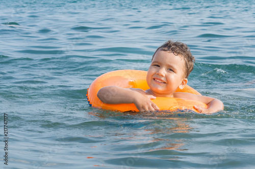 A happy child bathes in the sea on an inflatable circle