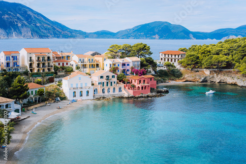 Cute blue sea bay in front of Assos village. Beautiful view to vivid colorful houses near blue turquoise colored transparent bay lagoon. Kefalonia, Greece