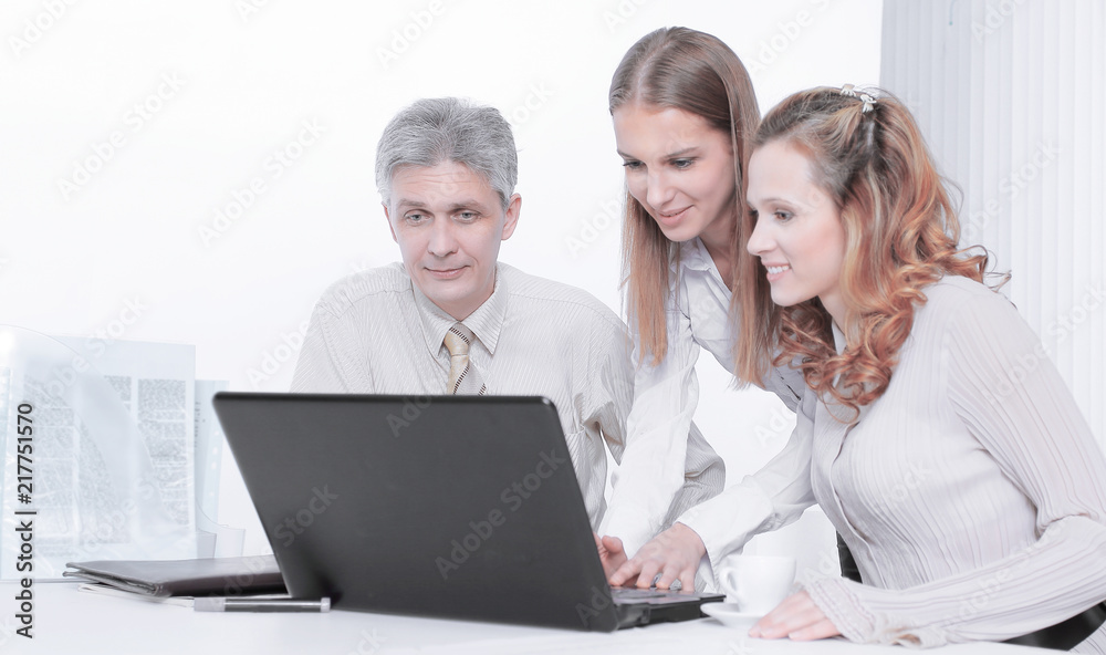 senior Manager and employees looking at laptop screen senior Manager and employees looking at laptop screen