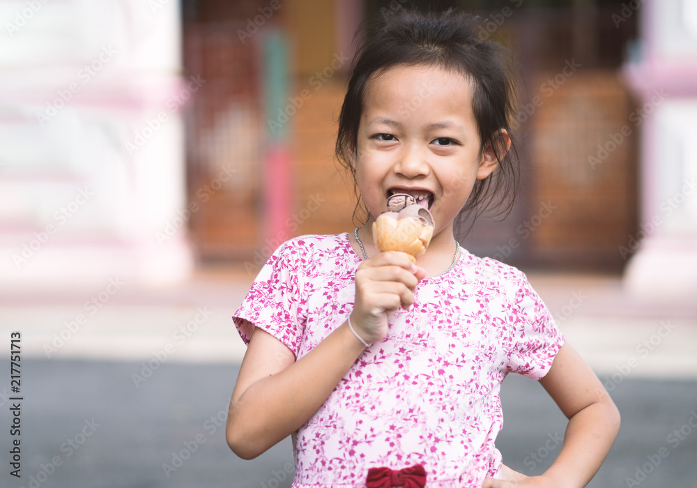Asian little girl eating ice cream at home.