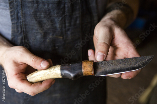 Midsection of blacksmith holding knife while standing in workshop photo
