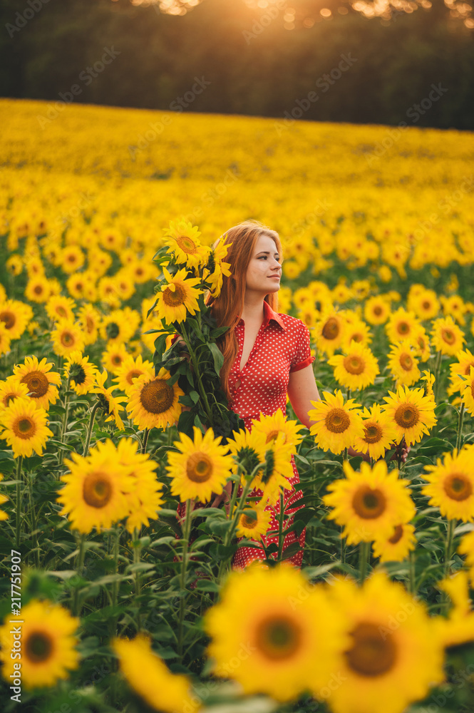 Beautiful girl in a huge yellow field of sunflowers.