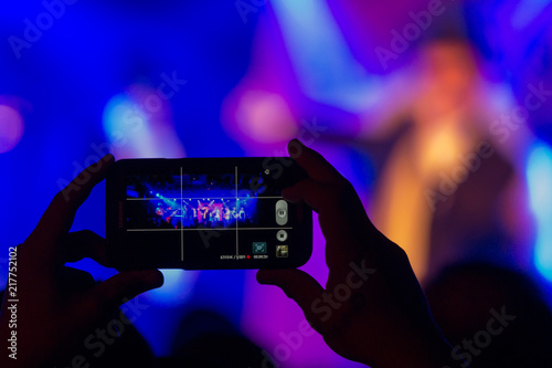 A person is filming a concert with a smartphone
