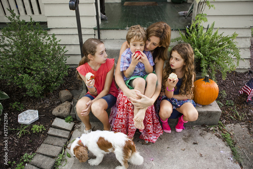 High angle view of children eating apples while sitting with mother on steps photo