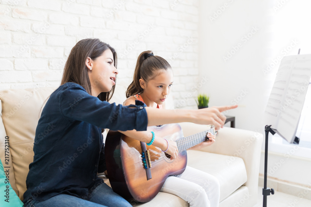 Teacher Pointing While Teaching Girl To Play Guitar Teacher Pointing While Teaching Girl To Play Guitar