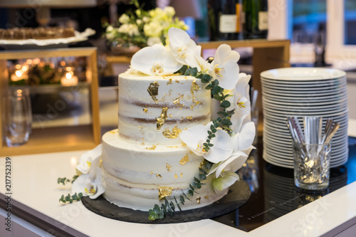 Wedding cake with cream and flower decoration and gold leaf