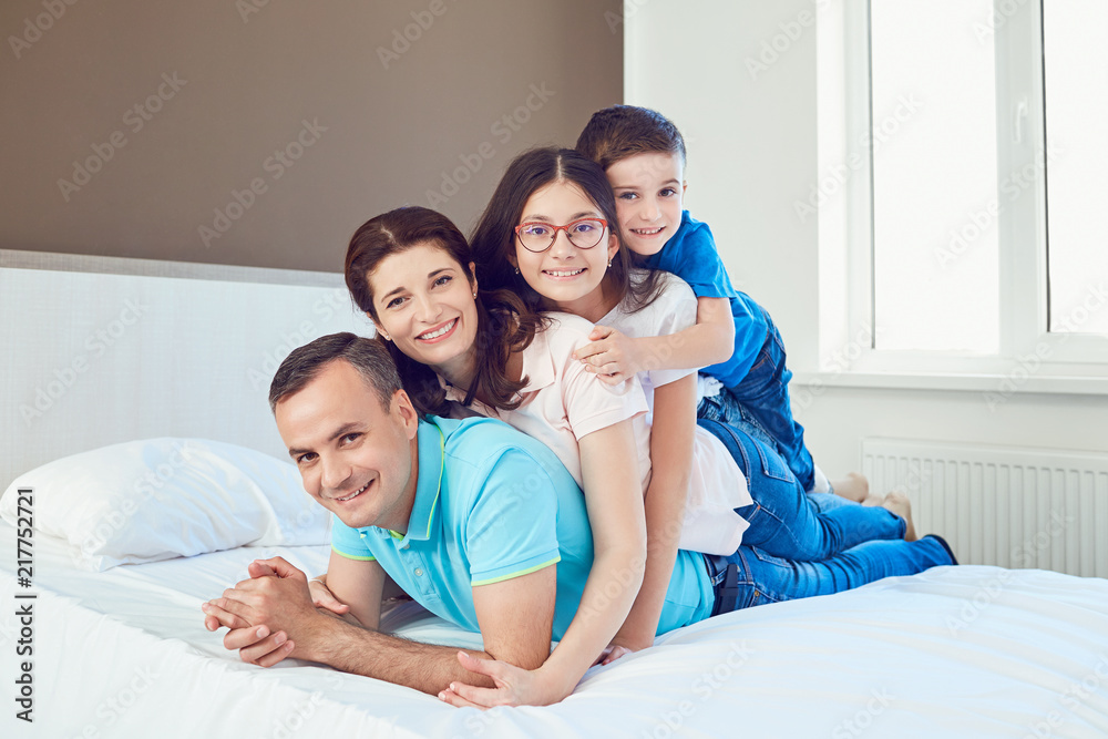 Portrait of happy family lying in bedroom.