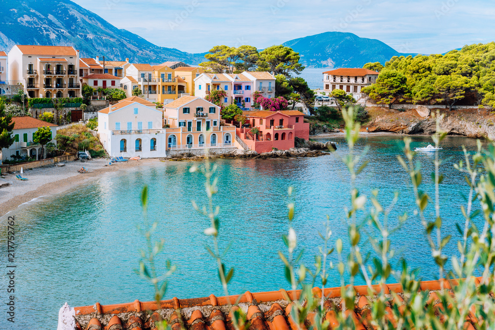 Assos village in Kefalonia, Greece. Turquiose bay, quite beach and colored traditional houses. Red roofs in front