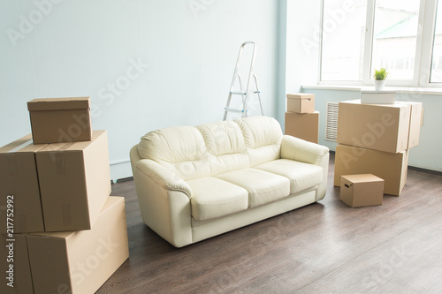 New home, relax, moving, furniture concept - a new white sofa in empty room between an amount of boxes