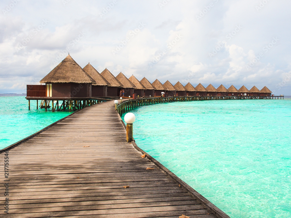 Tropical water villa bungalow and wooden bridge over the turquoise water  sea in Maldives island for summer vacations holiday concept.