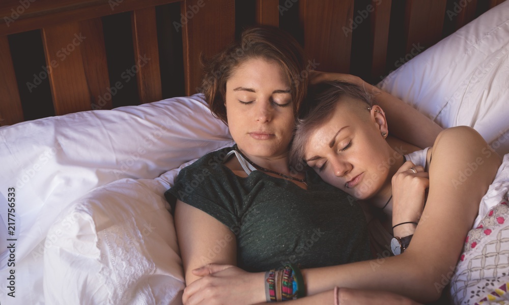 Lesbian couple sleeping on bed in bedroom Stock Photo | Adobe Stock