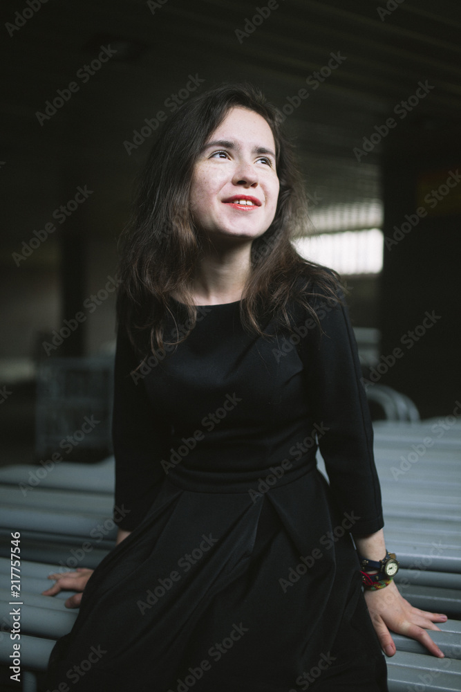 Thoughtful happy woman looking away while sitting on metal in factory Thoughtful happy woman looking away while sitting on metal in factory