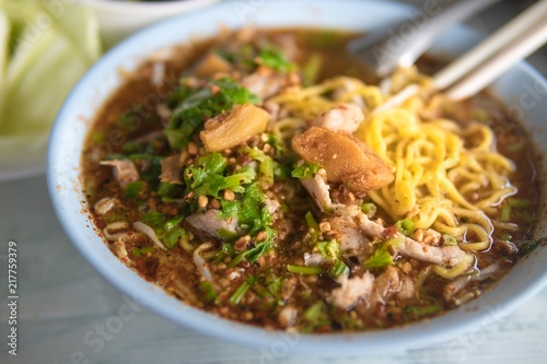 A bowl of Thai yellow noodle tom yum with pork and spicy."Thai noodles tom yum" popular Thai dish cuisine.