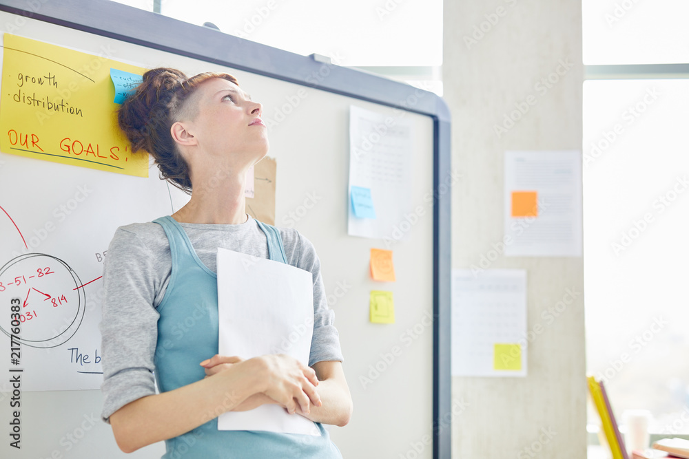 Nervous student in casualwear leaning against whiteboard in classroom before lesson or seminar Nervous student in casualwear leaning against whiteboard in classroom before lesson or seminar