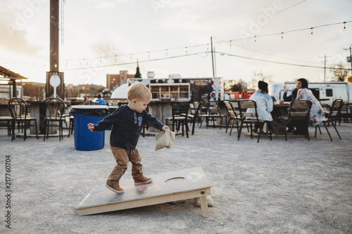 Boy playing cornhole at sidewalk cafe during sunset photo