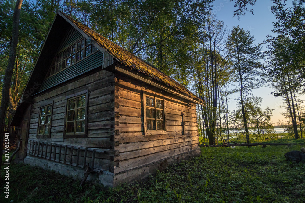 Old wooden house on the edge of forest near the lake Svir at sunrise