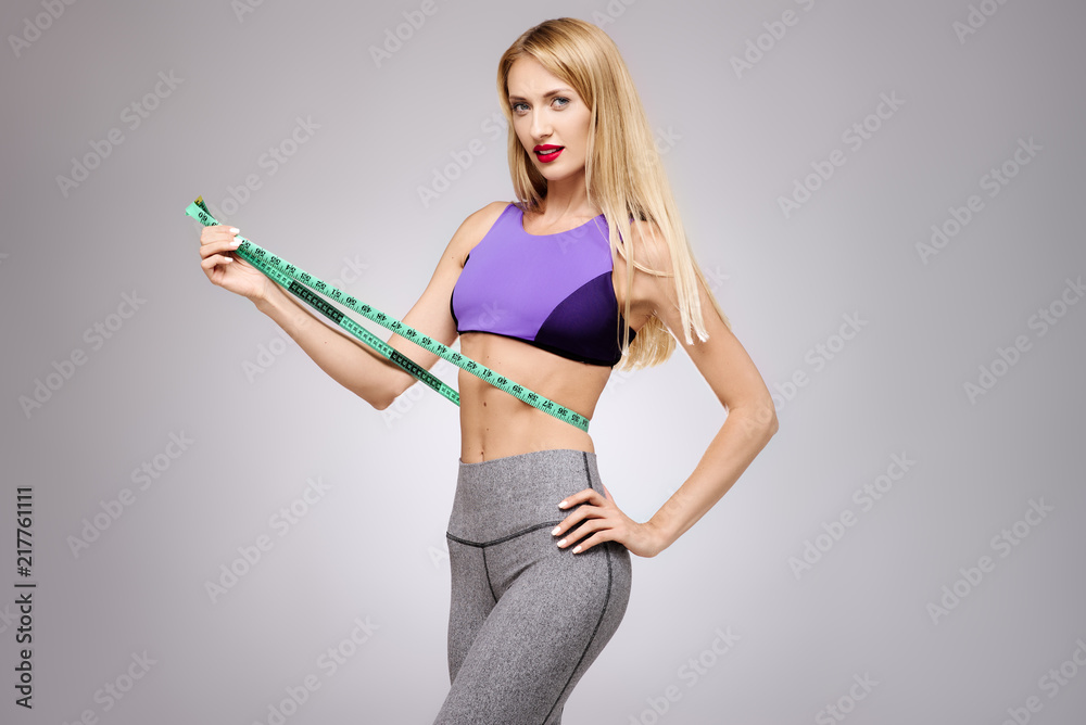 Young beautiful slim girl measuring her waist. Woman body with  measure-beauty, diet, slimming and weight loss concept. Isolated portrait  studio Stock Photo